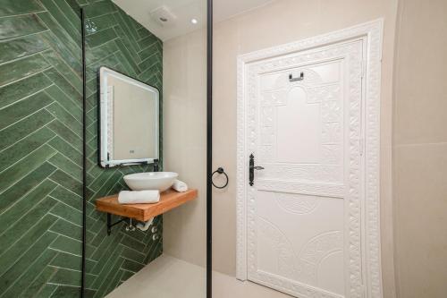 a bathroom with a sink and a mirror and a door at Taghazout Bay Chic Residence Sea View in Tamraght Ouzdar