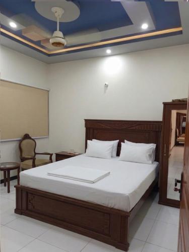 a bedroom with a large bed with a board on the ceiling at Nursery Suites in Karachi