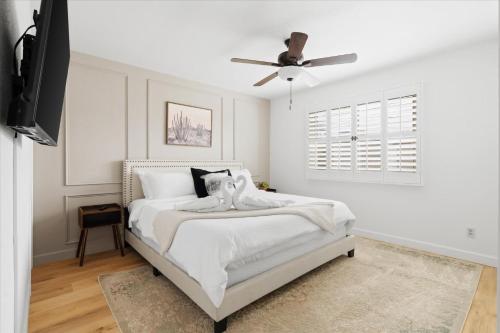 a bedroom with a white bed with a ceiling fan at Phoenix Getaway, Poolside Oasis, & Tesla Charger in Phoenix