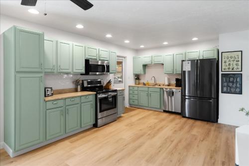 a kitchen with green cabinets and a refrigerator at Phoenix Getaway, Poolside Oasis, & Tesla Charger in Phoenix