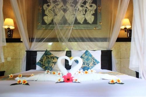 un lit avec deux swansfondus pour ressembler à des cœurs dans l'établissement Pondok Shindu Guest House, à Pemuteran