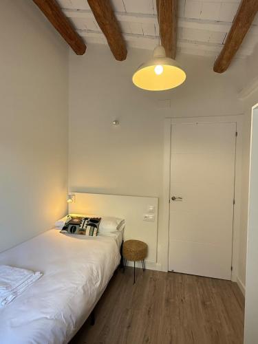 a white bedroom with a bed and a lamp at Casa Centenaria 1769 in Cubelles