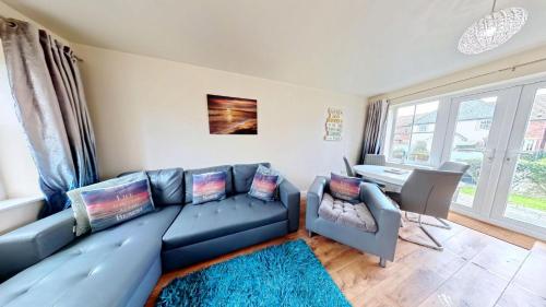 a living room with a blue couch and a table at Sunset Cottage - Part of the The Bay Filey Holiday Village with pool, gym and direct beach access, pub, restaurant, tennis and meadows walks in Filey