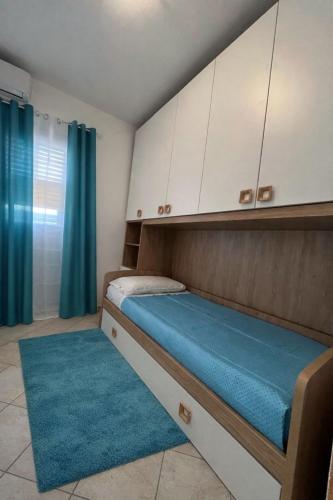 a bedroom with a bed with white cabinets and a blue rug at perla house in Valledoria