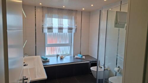 a bathroom with a sink and a toilet and a window at Panorama Wohnung in Künzelsau