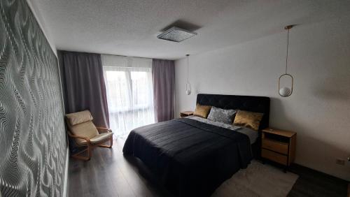 a bedroom with a bed and a chair and a window at Panorama Wohnung in Künzelsau