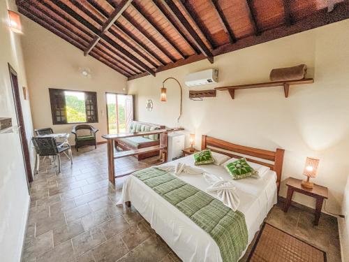 a bedroom with a bed and a desk in a room at Pousada Alem das Formas in Carrancas