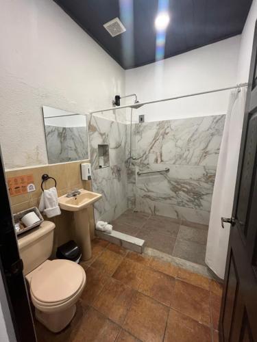 a bathroom with a shower and a toilet and a sink at Hotel y Restaurante Posada Real in Quetzaltenango