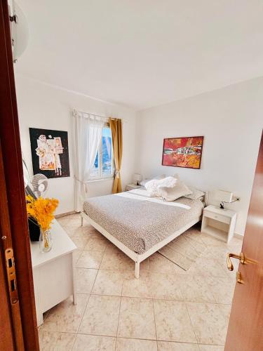 a white bedroom with a bed and a window at Appartamento Moneglia Holidays in Moneglia