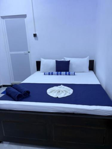 a bed with a blue blanket and a white shirt on it at Clara's Beach Inn in Trincomalee