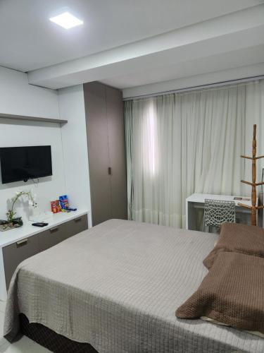 a bedroom with a bed and a desk and a television at West Fit Padrão 05 in Mossoró