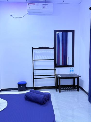 a blue room with a bed and a mirror at Clara's Beach Inn in Trincomalee