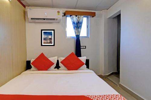 a bedroom with a bed with red pillows and a window at Hotel O Jalan Regency in Kolkata