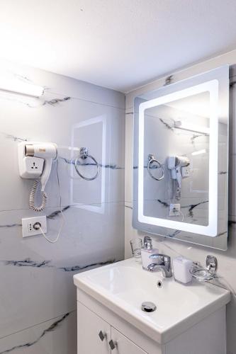a white bathroom with a sink and a mirror at Villa Kevin's in Sarandë