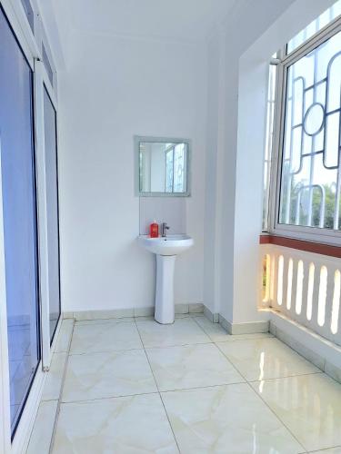 a white bathroom with a sink and a mirror at Laxury3BR Mins to Nyali Beach fast WiFi Netflix AC and Free Parking Near wild waters in Mombasa