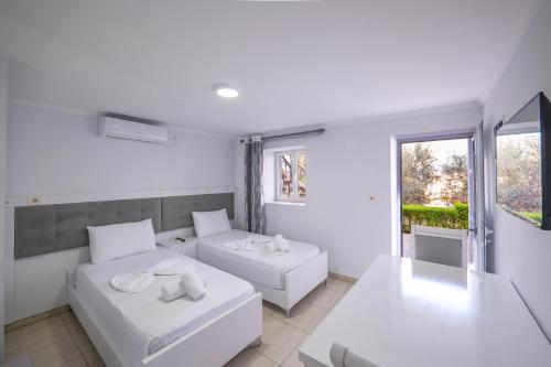 a white room with two beds and a window at Villa Kevin's in Sarandë