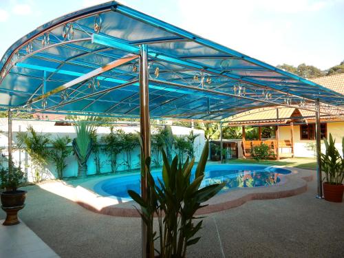 un grand auvent bleu au-dessus d'une piscine dans l'établissement Baan Malee, à Ban Tha Sao Kradong