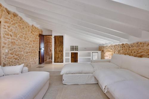 a living room with white furniture and a stone wall at Mansión Santa María in Santa Maria del Camí