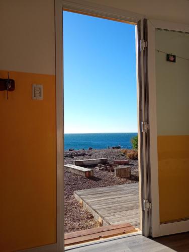 an open door with a view of the beach at Refugio Vegetariano El Mallín - sobre playa in Camarones