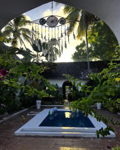 a swimming pool in a garden with a chandelier at Kimulimuli Wellness Spa Hotel in Bwejuu