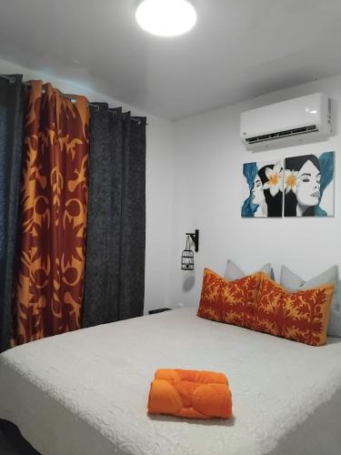 a bed with an orange pillow on top of it at Heikauiki home in Uturoa