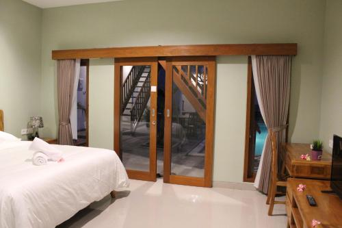 a bedroom with a bed and sliding glass doors at Naturela in Uluwatu