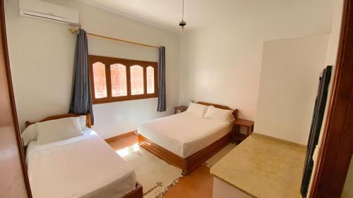 a small room with two beds and a window at RESIDENCE OUARZAZATE in Ouarzazate