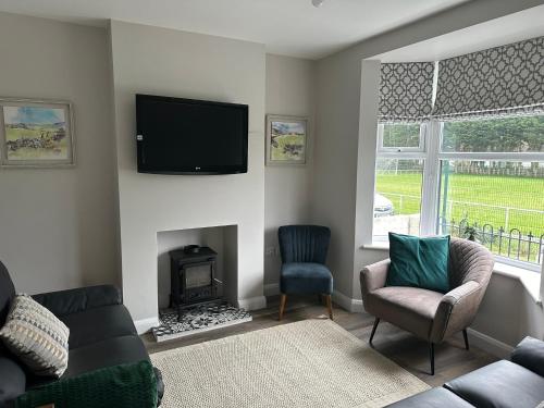 a living room with a fireplace and a tv on the wall at Homely house, foot of Snowdonia with private parking in Llanberis