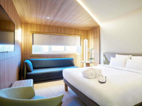 a hotel room with a bed and a blue couch at Novotel Marne La Vallée Collégien in Collégien