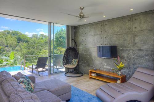 a living room with a couch and a tv on a wall at Villa Los Laureles III, Private Pool, Nature Trails, Beaches in Esterillos Este