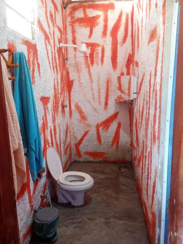 a bathroom with a toilet with red graffiti on the wall at Hostel Mamitchesca in Canoa Quebrada