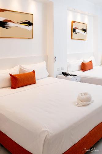 a bedroom with two beds with white sheets and orange pillows at Stars Hotel Bavaro in Punta Cana