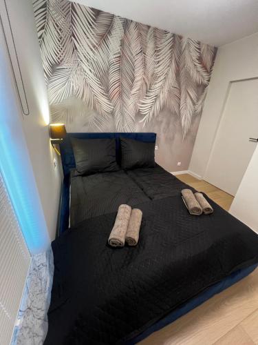 a bedroom with a black bed with two slippers on it at Apartment Comfort Premium in Bartoszyce