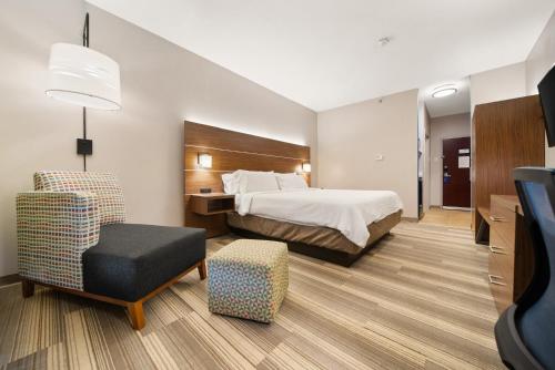 a hotel room with a bed and a chair at Holiday Inn Express Trincity by IHG in Piarco