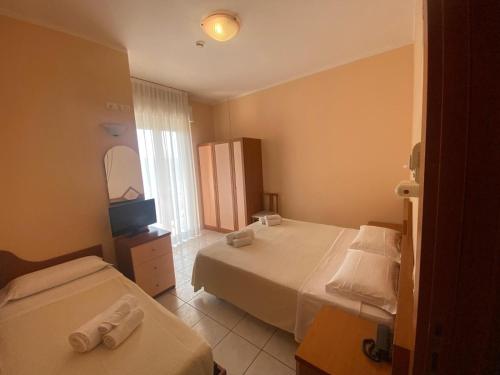 a hotel room with two beds and a television at Hotel HARRY'S Hospitality Riccione-Fronte Mare in Riccione
