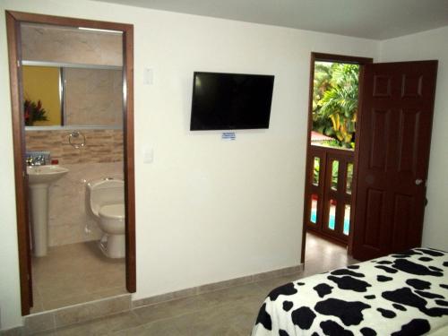 a bedroom with a bathroom with a television on a wall at Cabañas Las Bifloras in Santa Rosa de Cabal