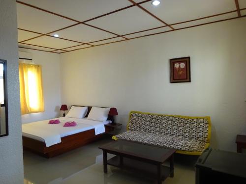 a bedroom with a bed and a couch in it at Bohol Sunside Resort in Panglao