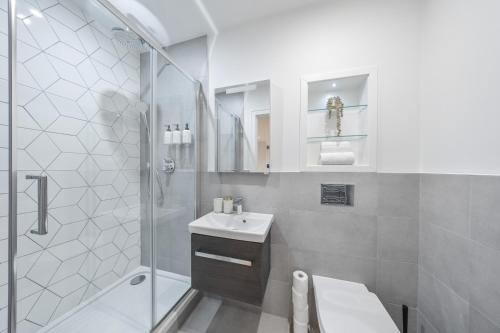 a white bathroom with a shower and a sink at Modern & Cozy 2-Bedroom Apartment plus Parking, Gym, Cinema, Games Room, Workspace in New Malden
