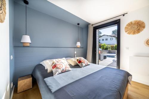a bedroom with a large bed and a large window at Small house with swimming pool and jacuzzi in Biarritz