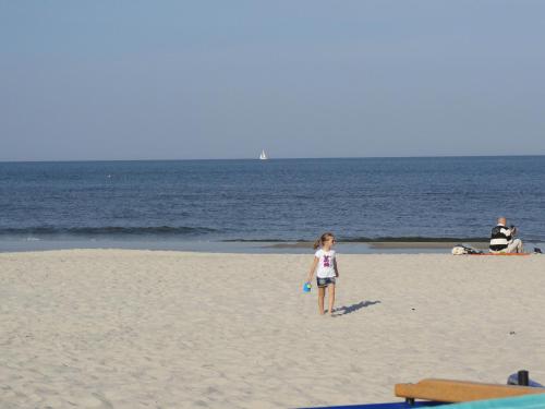 a young girl standing on the beach with a frisbee at Apartament 316 w Domu Zdrojowym in Jastarnia