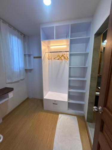 a walk in closet with white shelves and a door at Seaside Drift in Huraa