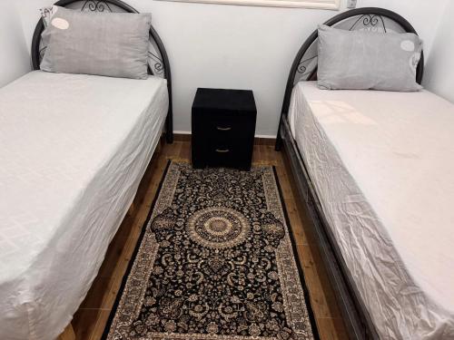 two twin beds with a rug in a room at Dar yasmine in Azrou