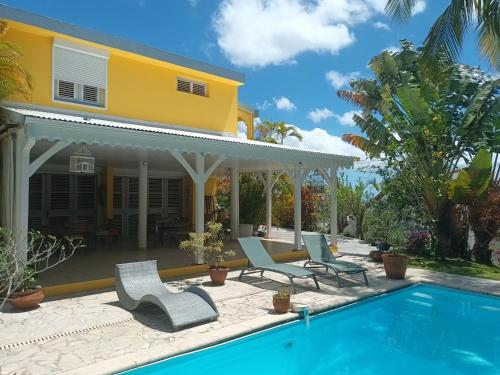 a house with a swimming pool and a yellow house at Un séjour privilégié à La Villa Gialla chambre d'hôte et loft dans une maison de charme avec piscine à débordement in Schœlcher