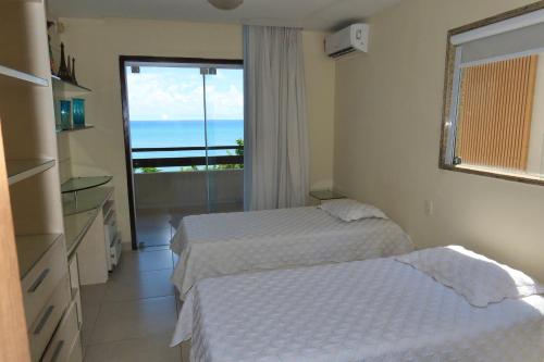 two beds in a room with a view of the ocean at Porto Brasil Resort - Casa de praia em condomínio de luxo in Parnamirim