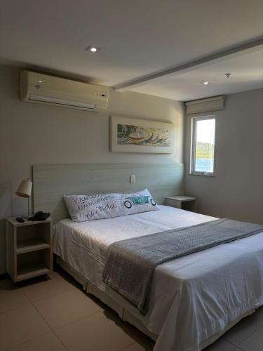 a bedroom with a large white bed with a window at Apart Itacuruçá - Hotel Porto Marina in Mangaratiba