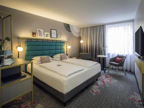 a hotel room with a large bed and a television at Mercure Wien Zentrum in Vienna