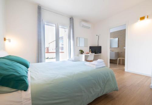a white bedroom with a large bed and a window at Corona Guest House in Sestu
