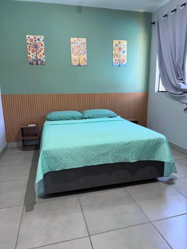 a bedroom with a bed with a green comforter at Casa aconchegante in Timbó