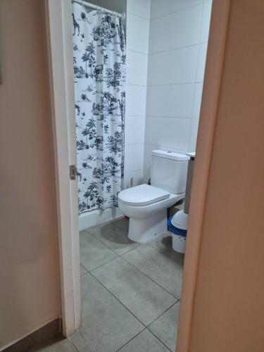 a bathroom with a toilet and a shower curtain at Depto cómodo y central in Temuco