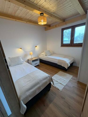 two beds in a room with two windows at Domki Mazury Mikołajki in Mikołajki